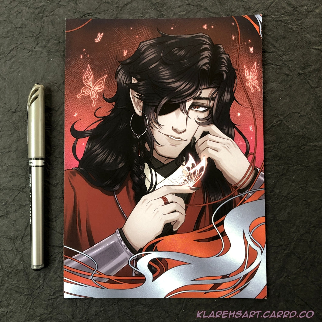 Illustration of a man with long black hair and eyepatch holding a glowing silver butterfly on his fingertip. He is wearing red, white, and black, with silver jewelry. A red background with more glowing butterflies surround him. The ink pen on the left shows size comparison. This is the Medium Size.