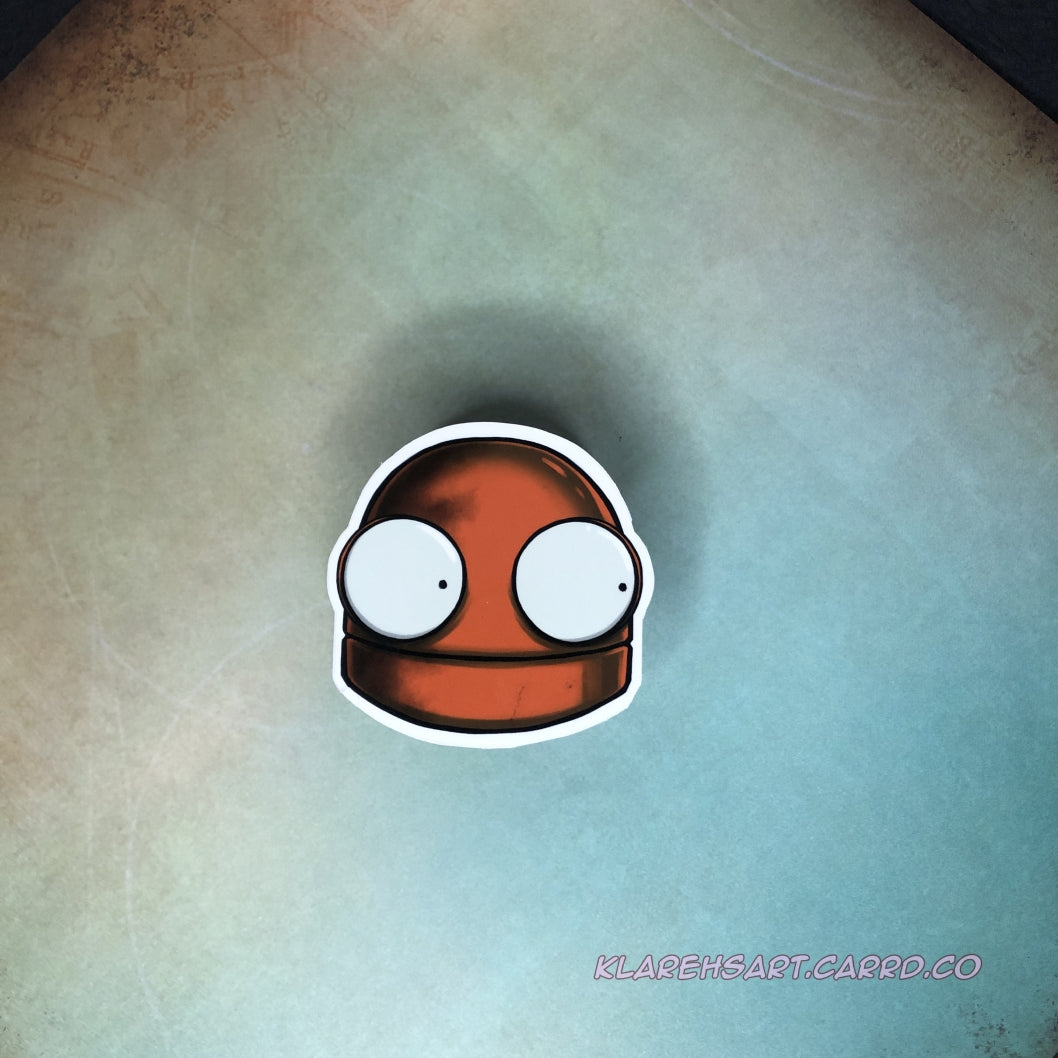 An orange vinyl sticker of a robot head. It's eyes wide with fright. It is above a gold & green background.