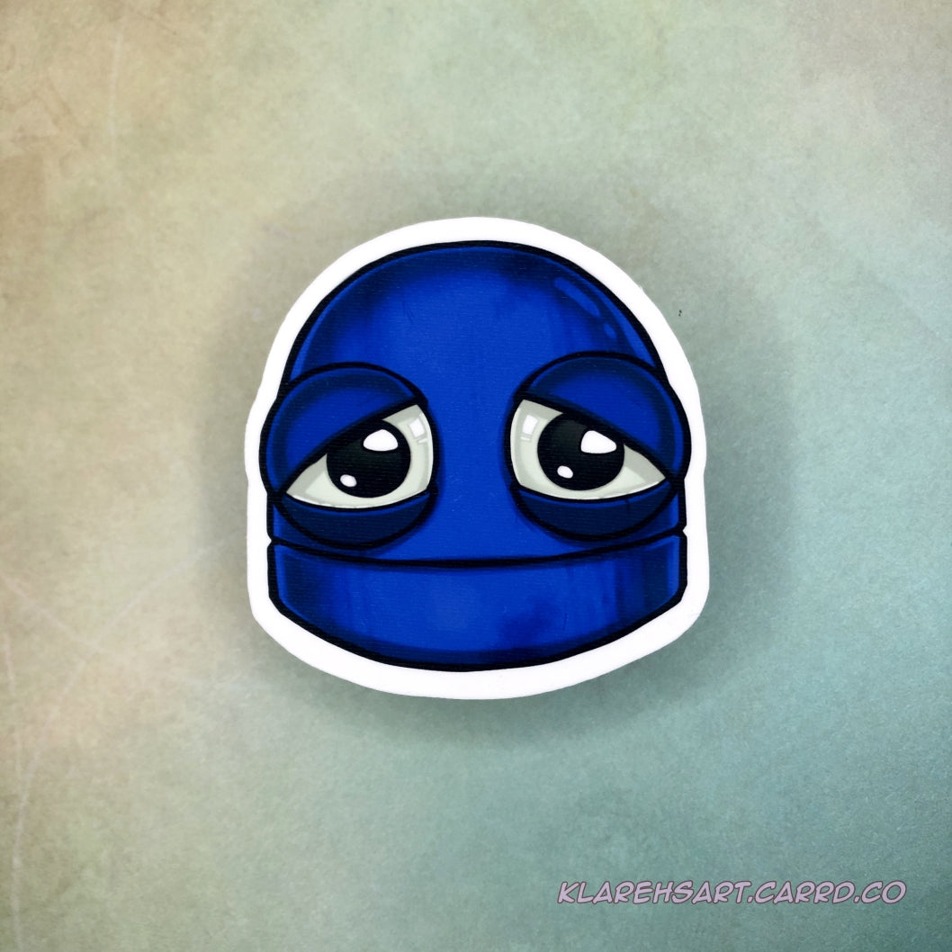 A vinyl sticker of a blue robot with a sad expression. It rests on a light gold and green background.