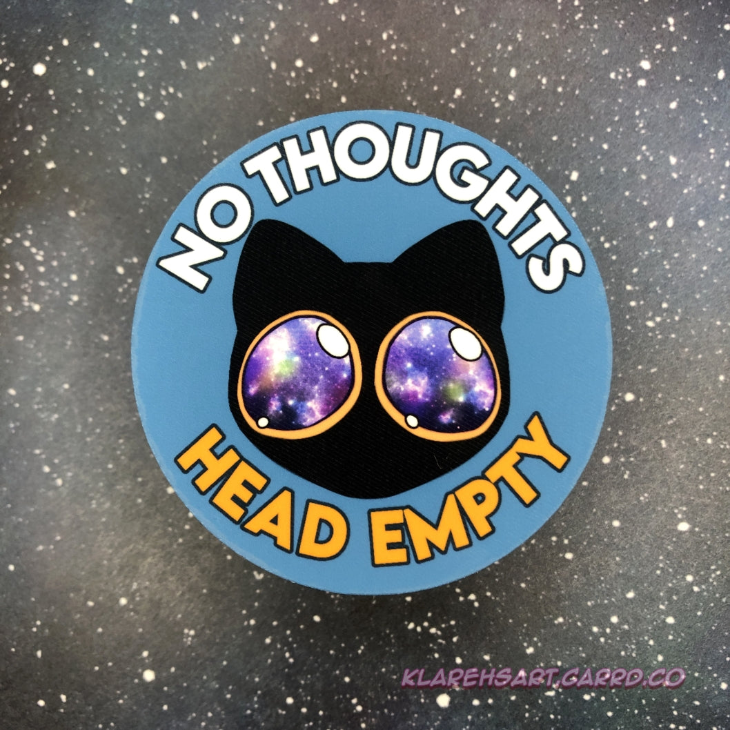 Circular sticker with a black cat with galaxy eyes and text 'No Thoughts Head Empty' on a starry background.