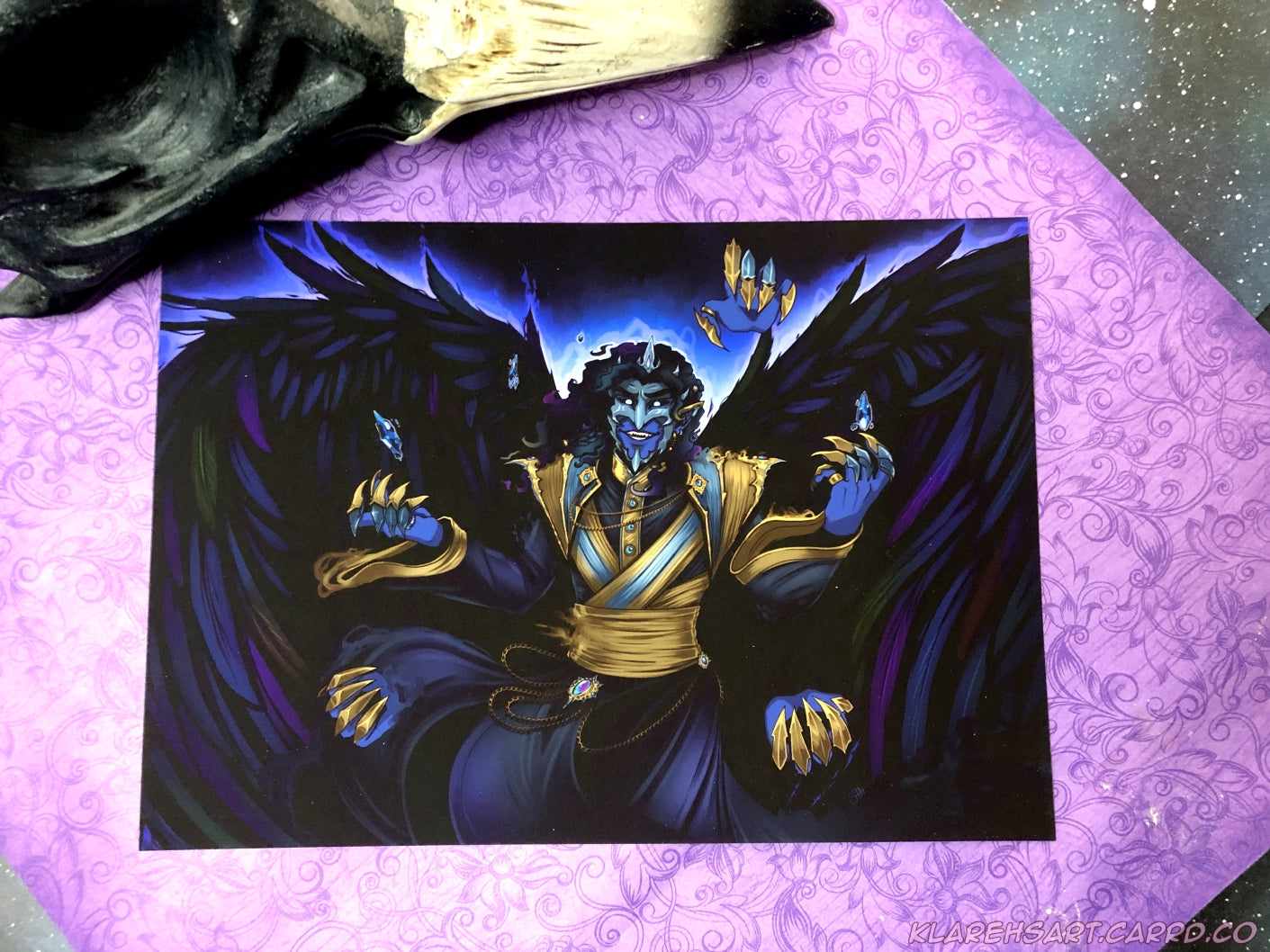 Colorful illustration of Ozul, an original character in Beyond the Stillwall. Ozul appears as a shadow like being with raven wings, 5 visible hands, with 3 of the hands floating detached. He is wearing indigo, black, and silver attire. His face is covered in a sharp metal mask. This is the medium size.