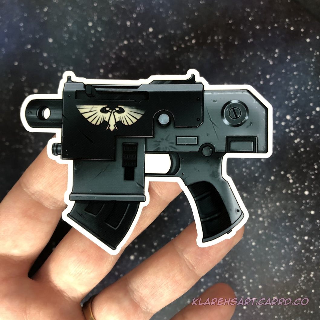 A hand holding a black and green gray bolt gun pistol sticker with a futuristic theme. Roman double headed eagle adorns the side. Resting on a starry background.